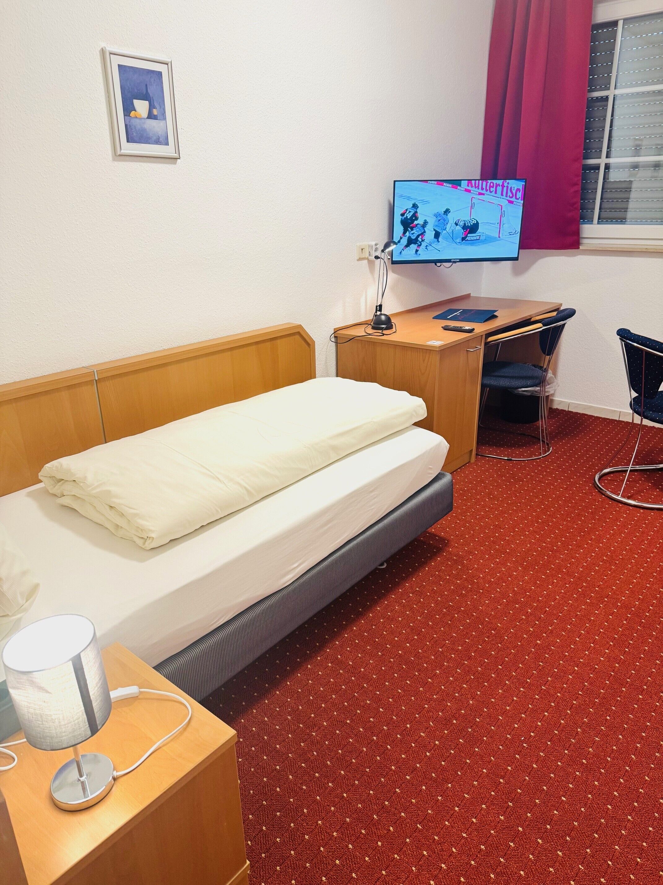 Una habitación de hotel con una cama, un escritorio, una silla, un televisor y una lámpara.