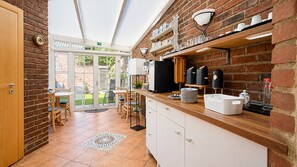 Una cocina con pared de ladrillo, encimera de madera, pileta y comedor con sillas y mesa.