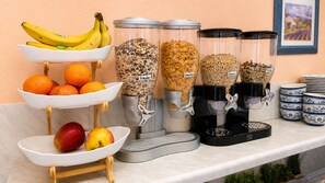 Una barra de desayuno con cuencos de fruta, granola y cereales.
