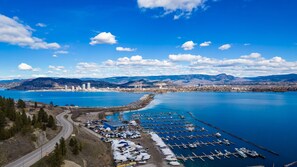 Un puerto deportivo con barcos amarrados, un puente y un paisaje urbano con montañas al fondo.