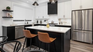 A modern kitchen with a central island, stainless steel appliances, and pendant lighting. - Waterfront Home with
      Rooftop Hot Tub (West Kelowna)