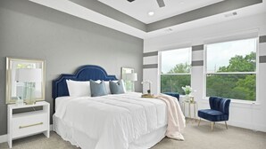 Une chambre dotée d’un grand lit, d’un ventilateur de plafond et offrant une vue sur l’extérieur par les fenêtres.