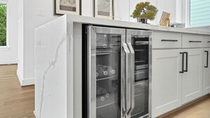 Une cuisine moderne dotée d’un réfrigérateur et d’un four encastrés, de meubles blancs et d’une fenêtre donnant sur un paysage verdoyant.