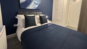 A bedroom with a bed, a nightstand, a wall-mounted artwork, and a wardrobe. - Spacious 5BR Watford Home - Sleeps 10 - Parking (Watford)