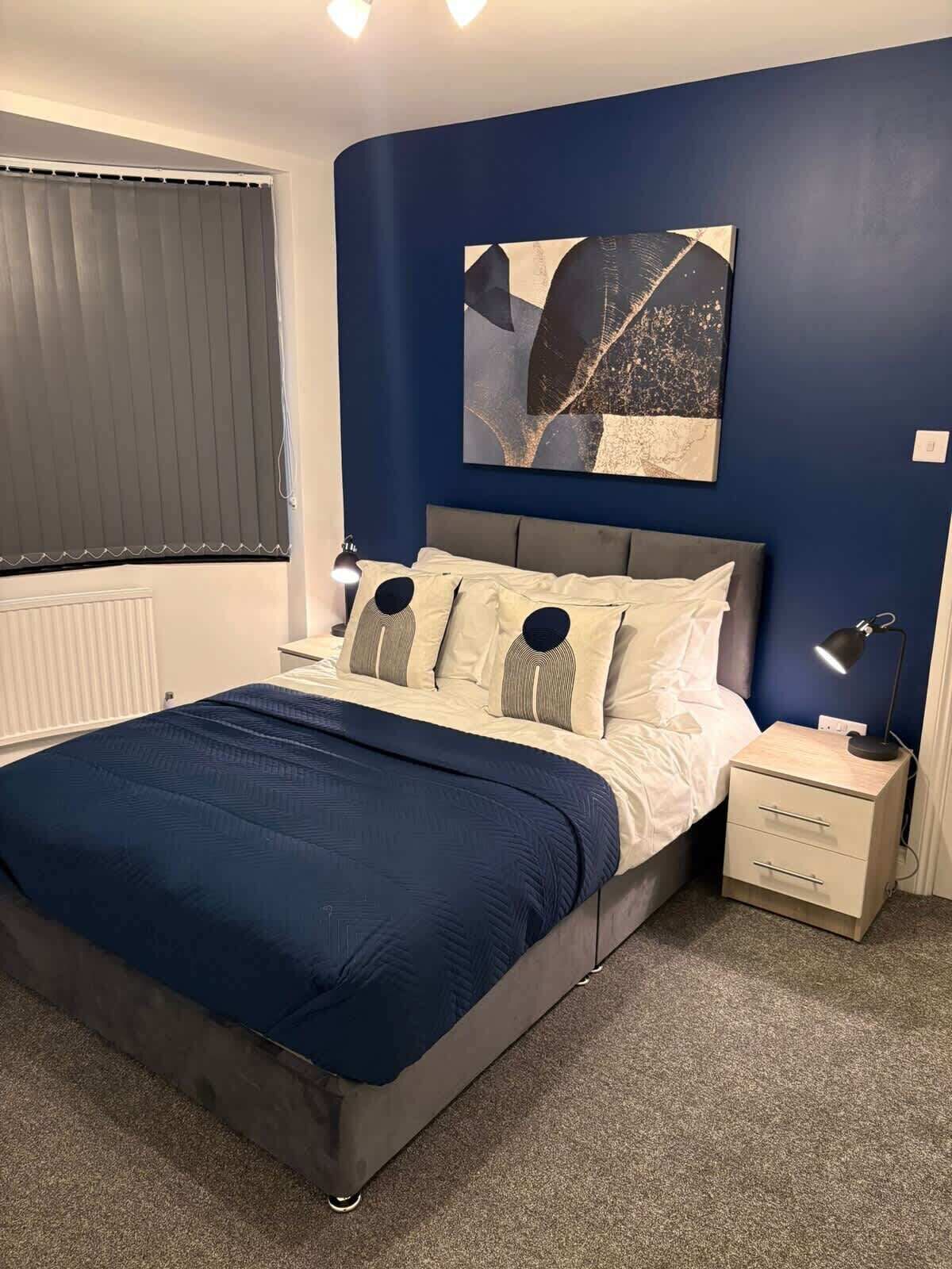 Une chambre à coucher avec un lit, une table de chevet, une lampe et un tableau au mur.