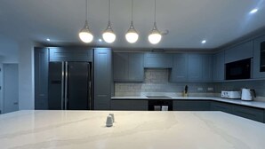 A modern kitchen with a large island, stainless steel appliances, and pendant lighting. - Spacious 5BR Watford Home - Sleeps 10 - Parking (Watford)