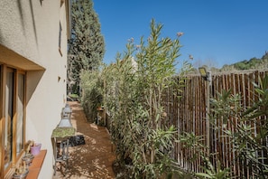 A narrow outdoor corridor with a wooden fence, potted plants, and a clear blue sky. - Rural House 'Casa Agapito Marazuela' with Mountain Views, Private Garden, and Wi-Fi (Segovia)