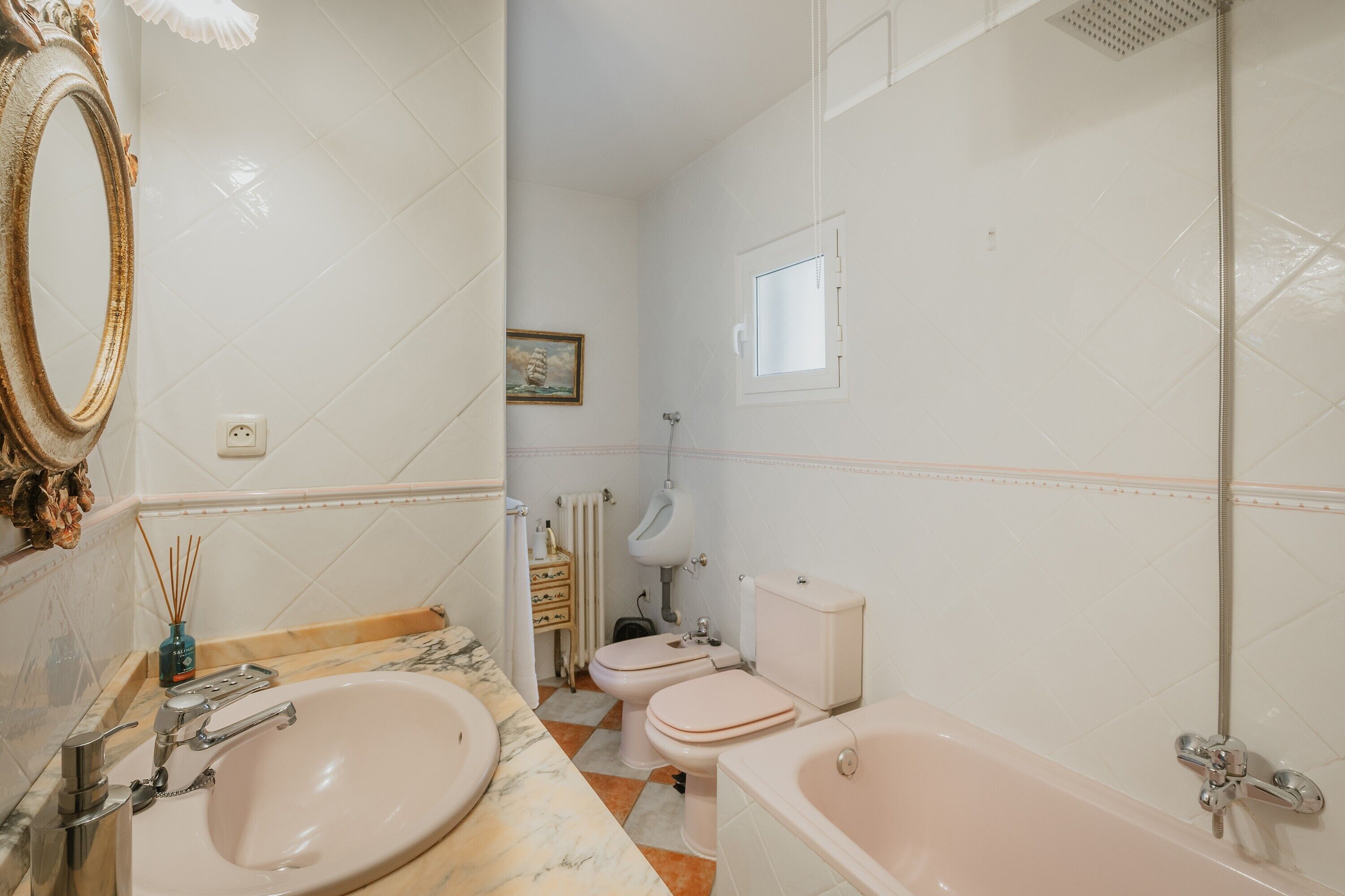 Un baño con lavamanos, inodoro, bañera y espejo.