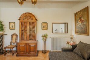 A room with a wooden cabinet, a sofa, a chair, a radiator, and framed pictures on the wall. - Rural House 'Casa Agapito Marazuela' with Mountain Views, Private Garden, and Wi-Fi (Segovia)