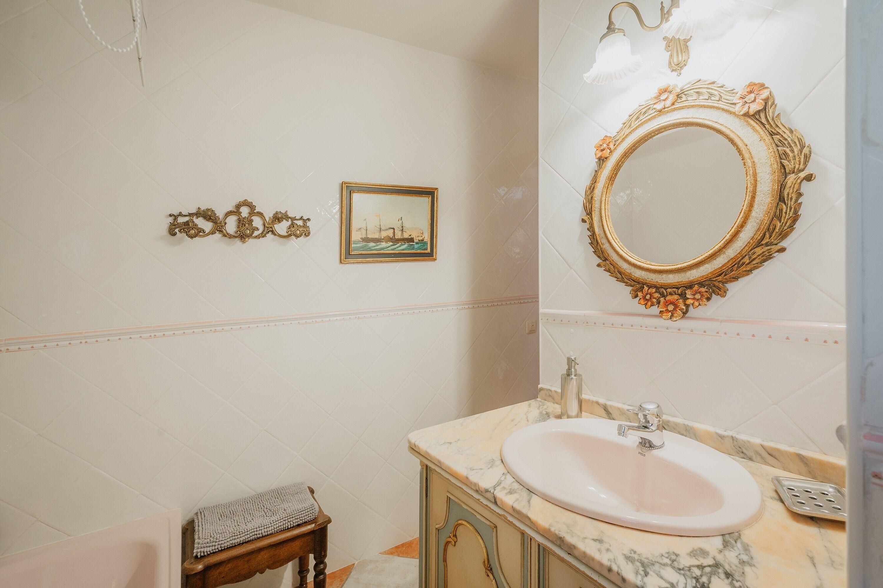 Une salle de bain avec un lavabo en marbre, un miroir décoratif et un tableau encadré au mur.