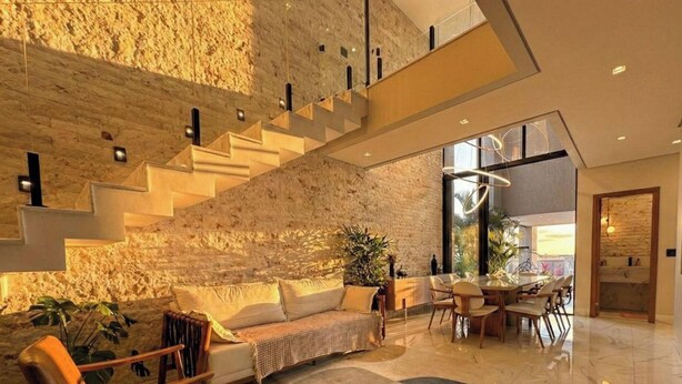 A spacious living area with a high ceiling, a staircase, a dining area, and a kitchen visible through an open door. - Moto GP Goiânia - Casa Premium - Piscina (Senador Canedo)