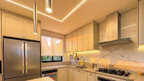 A modern kitchen with stainless steel appliances, marble countertops, and pendant lighting. - Moto GP Goiânia - Casa Premium - Piscina (Senador Canedo)