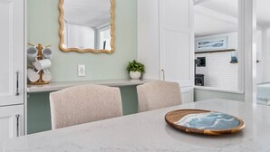 Een moderne keuken met een marmeren aanrechtblad, een spiegel met houten lijst en een eethoek met tafel en stoelen.