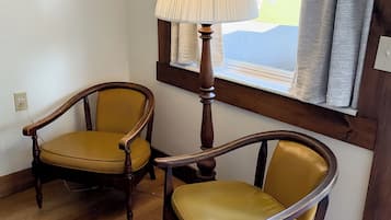 Two wooden chairs with yellow upholstery in a room with wooden flooring and a window with curtains.