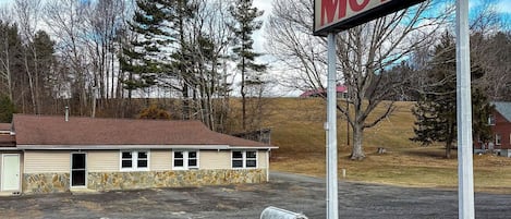 A motel sign, a building with a stone facade, and a mailbox.