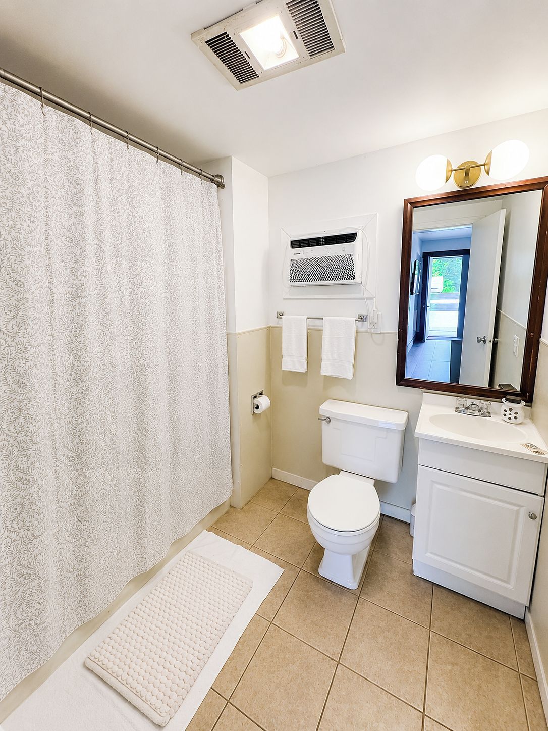 Un baño con cortina de ducha, inodoro, lavabo y espejo.