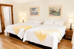 A double bed room with two bedside tables, each with a lamp, and two framed paintings on the wall.