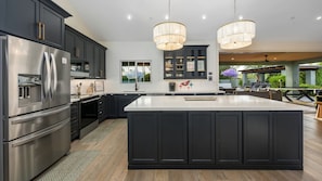 A modern kitchen with dark cabinetry, stainless steel appliances, and a large island. - Kierland Luxury 5BR Retreat w/ Pool, Spa, Golf Sim, Putting Green & Sport Court (Scottsdale)