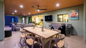 A room with a wooden table and chairs, a bar area, and a television. - Kierland Luxury 5BR Retreat w/ Pool, Spa, Golf Sim, Putting Green & Sport Court (Scottsdale)