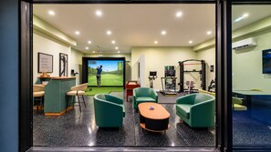 A room with a golf simulation setup, exercise equipment, and seating. - Kierland Luxury 5BR Retreat w/ Pool, Spa, Golf Sim, Putting Green & Sport Court (Scottsdale)
