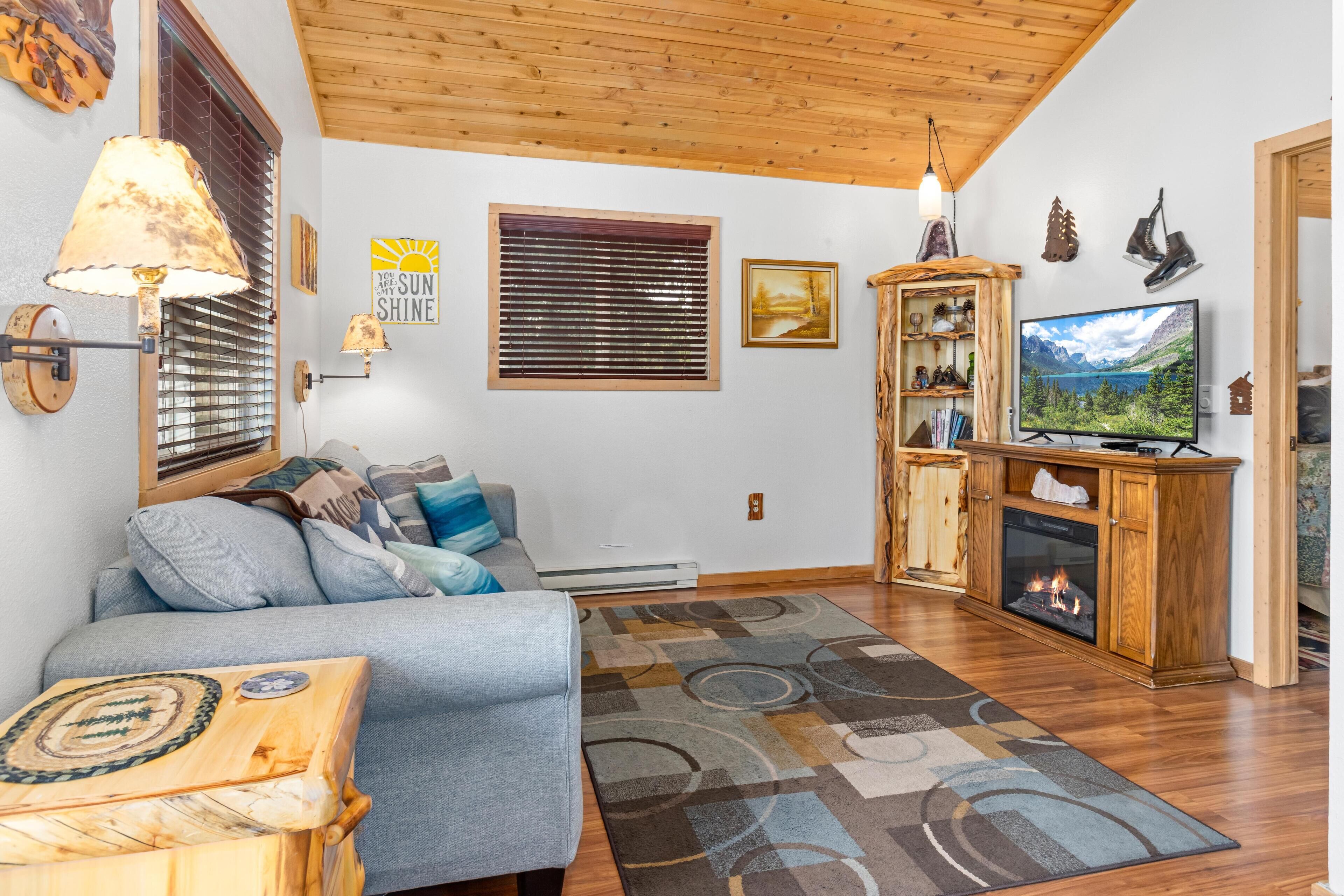 A cozy living room with a grey sofa, wooden cabinet, and a fireplace.