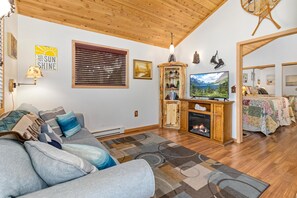 A cozy living room with a sofa, TV, wooden cabinet, and a fireplace.