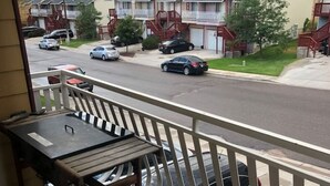 Un terrazzo in legno con ringhiera curva che si affaccia su una strada con auto parcheggiate e case.