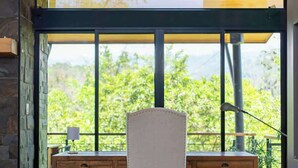A modern office space with a large window, wooden desk, and two drawers.