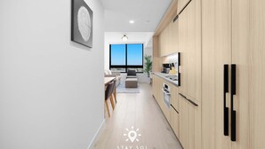 Una cocina moderna con armarios de madera, una zona de comedor con sofá y sillas, y un ventanal con vistas.