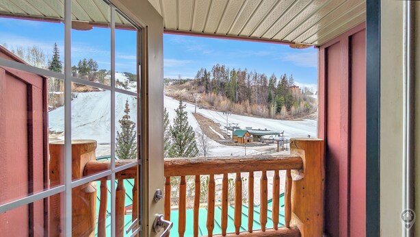 Een houten balkon met uitzicht op een besneeuwd landschap en een skibaan.