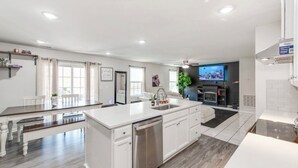 Une cuisine moderne avec des meubles blancs, un îlot central et un four encastré.