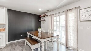A dining area with a wooden table and benches, a dark accent wall, and a window with curtains.