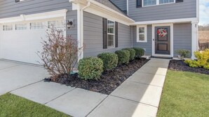 A two-story house with a garage, a front porch, and a well-maintained lawn.