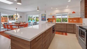 Een moderne keuken met een groot eiland, houten kastjes en hanglampen.