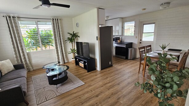 Una sala moderna con sofá, televisor y mesa de centro, una cocina equipada y un comedor con sillas y mesa.