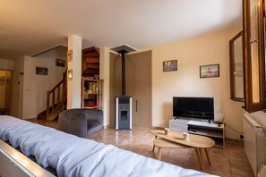 Un salon comprenant un canapé, un téléviseur, une table basse, une cheminée et une bibliothèque.