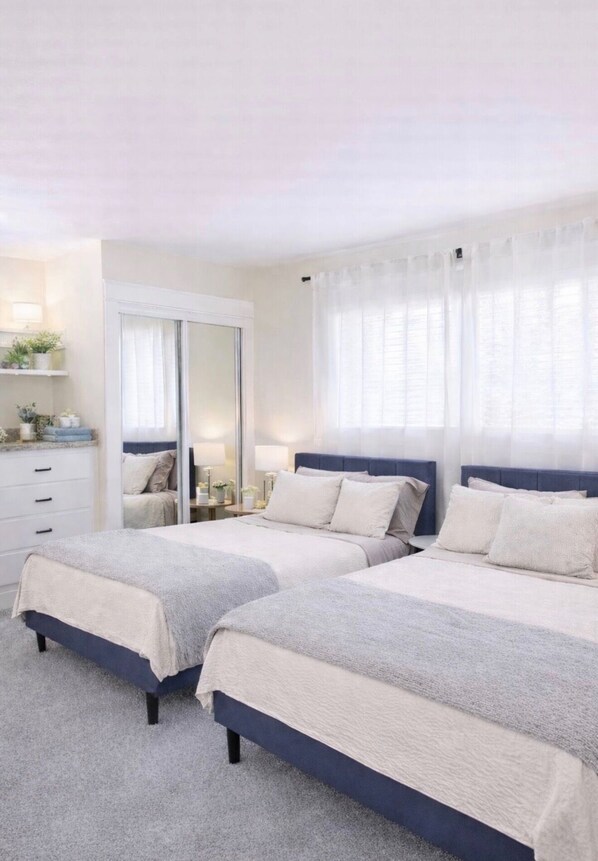A bedroom with two beds, a mirror, a dresser, and a window with sheer curtains. - 2BR Beach Escape-Steps to Manhattan Beach Pier (Manhattan Beach)