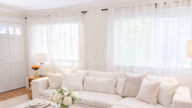 Ein geräumiges Wohnzimmer mit einem großen, weißen Ecksofa, einem Couchtisch und einem Teppich.