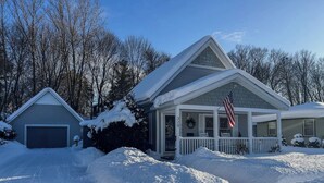 Una casa a due piani con garage, veranda coperta e vialetto innevato.