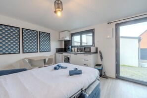 Ein modernes Schlafzimmer mit Bett, Schreibtisch und einer kleinen Küche.