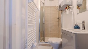 Un bagno con doccia vetrata, un water e un lavandino con specchio sopra.
