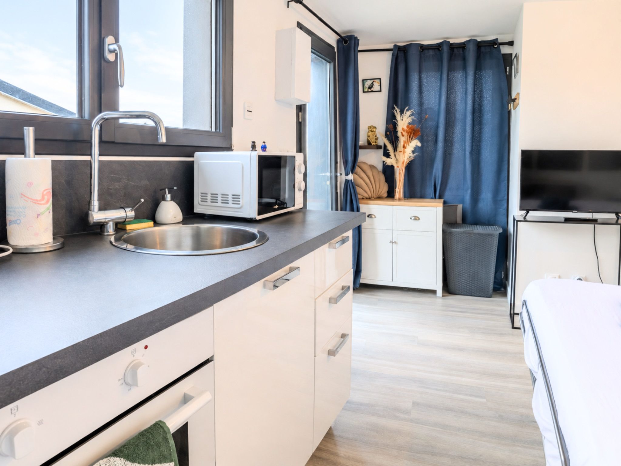 A modern kitchen with a sink, microwave, and a window.