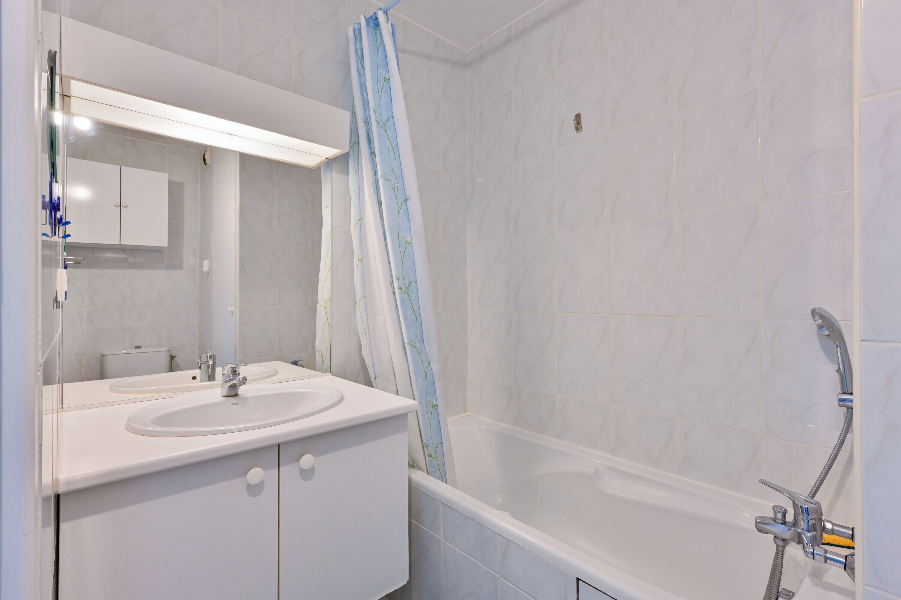 A modern bathroom with a white sink, mirror, and bathtub.