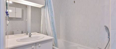 A modern bathroom with a white sink, mirror, and bathtub.