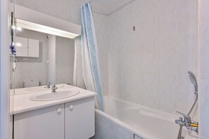 A modern bathroom with a white sink, mirror, and bathtub.