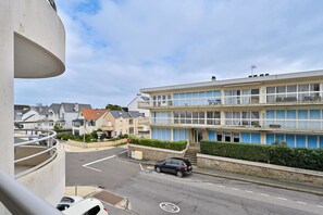 A multi-story building with balconies, a roundabout, and a car on the street.