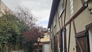 Ein schmaler Gang mit einem Pfad, einem Holzzaun und einem Gebäude mit traditioneller Fassade.