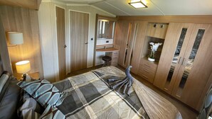 Un dormitorio con cama, escritorio, silla, espejo y armario.