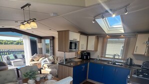 Una cocina moderna con armarios azules, un comedor con mesa dispuesta para cuatro, y vistas al exterior.