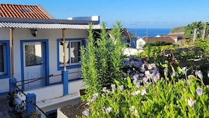Ein Küstengebäude mit blau-weißer Fassade, einem Ziegeldach und Blick auf das Meer.